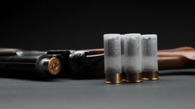Close-up: loaded shotgun and cartridges on the table, the man takes cartridge