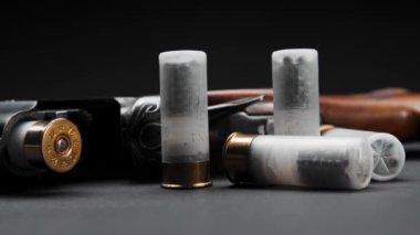 Close-up: loaded shotgun and cartridges on the table, the man takes cartridge