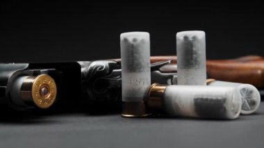 Close-up: loaded shotgun and cartridges on the table, the man takes cartridge