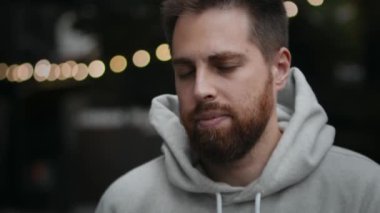 Close-up of a bearded attractive man smoking an electronic cigarette on the street in t evening