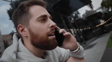 Close-up of a bearded man laughing and talking on phone