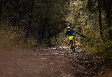 Ormandaki profesyonel motosiklet sürücüsü doğa yolundaki çamurdan geçer..