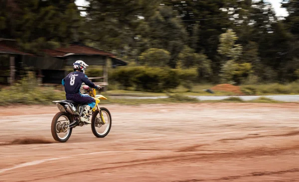 Ormandaki profesyonel motosiklet sürücüsü doğa yolundaki çamurdan geçer..