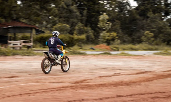 Ormandaki profesyonel motosiklet sürücüsü doğa yolundaki çamurdan geçer..