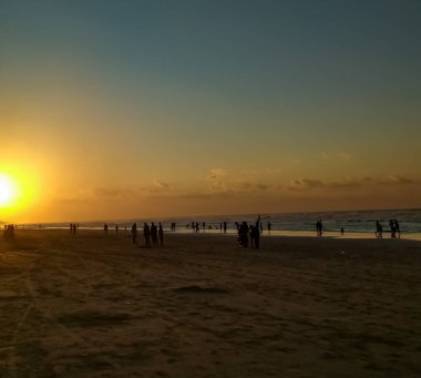 Sahilde gün batımı güzel bir siluet oluşturur.