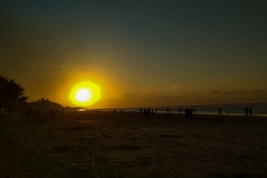 Sahilde gün batımı güzel bir siluet oluşturur.