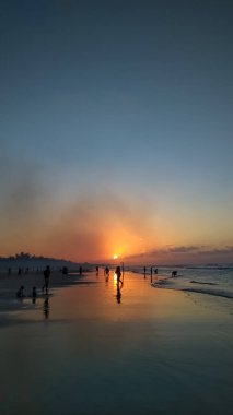 Sahilde gün batımı güzel bir siluet oluşturur.