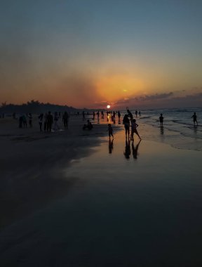 Sahilde gün batımı güzel bir siluet oluşturur.