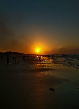 Sahilde gün batımı güzel bir siluet oluşturur.