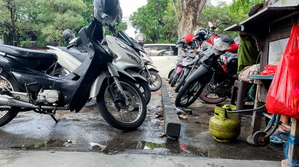 12 Mart 2022 Surabaya, Endonezya. Islak motosiklet yağmurdan sonra otopark, bir soto satıcısının yanında..