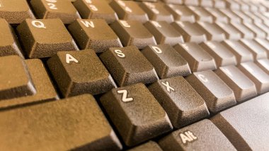 Tahta masadaki bilgisayar klavyesinin yakın plan görüntüsü.