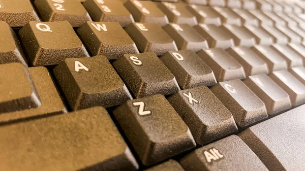 Tahta masadaki bilgisayar klavyesinin yakın plan görüntüsü.