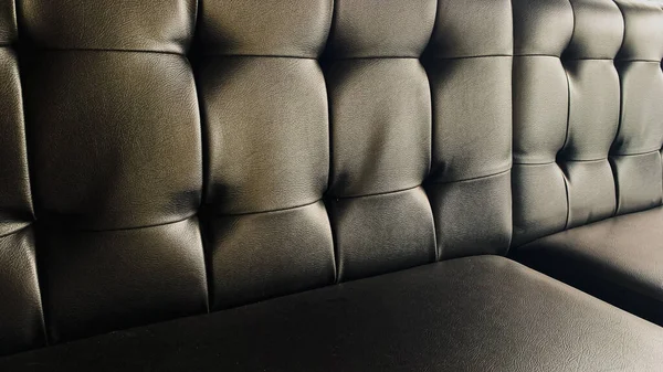 Deriden yapılmış, zarif siyah renkli bir kanepe.