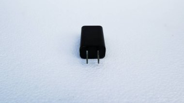 Beyaz arka planda siyah bir akıllı telefonu şarj etmek için adaptör