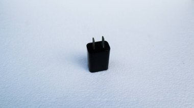 Beyaz arka planda siyah bir akıllı telefonu şarj etmek için adaptör