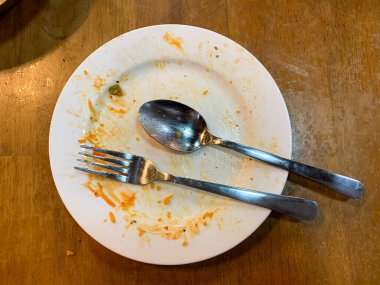 Kirli kaşığı ve çatalı olan beyaz bir tabak. Çünkü az önce restoranda yemek yemek için kullanıldı.