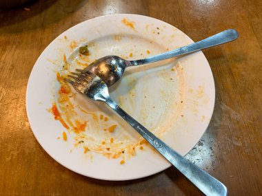 Kirli kaşığı ve çatalı olan beyaz bir tabak. Çünkü az önce restoranda yemek yemek için kullanıldı.