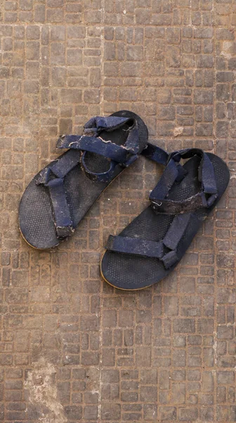 Siyah sandaletler ve mavi kayışlar giyiyordu. Sandaletler uzun zamandır giyilmedi..