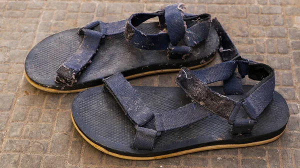 Siyah sandaletler ve mavi kayışlar giyiyordu. Sandaletler uzun zamandır giyilmedi..