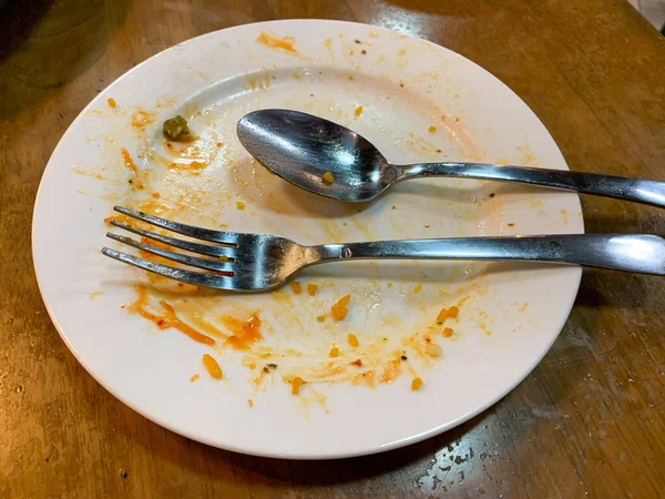 Kirli kaşığı ve çatalı olan beyaz bir tabak. Çünkü az önce restoranda yemek yemek için kullanıldı.