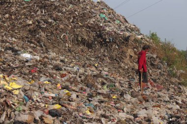 A man is walking on a mountain of garbage