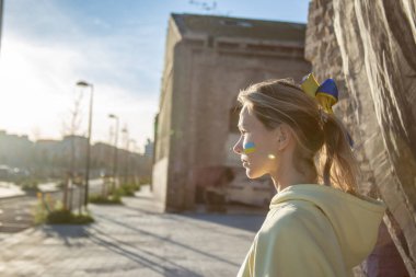 Yanağında bayrak olan ve savaş işareti olmayan Ukraynalı bir kadın. 