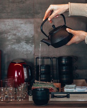 Elleri çaydanlıktan fincana çay dolduruyor.