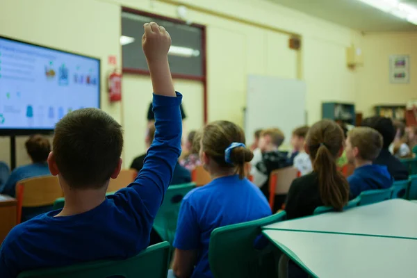 Okul çocukları kollarını kaldırıp öğretmene cevap vermeye hazır.