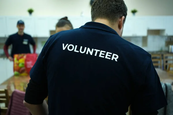 Mavi tişörtlü bir etkinlikte gönüllü çalışıyor.