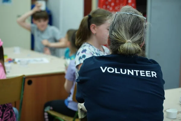 Okulda çocuklara yardım eden gönüllü.