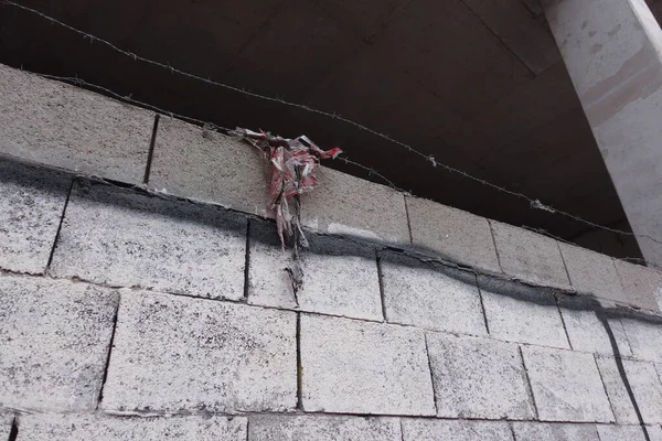 brick wall with a piece of cloth hanging on its wires
