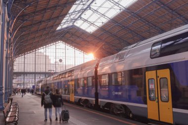 Two storey train at a station with passengers passing by