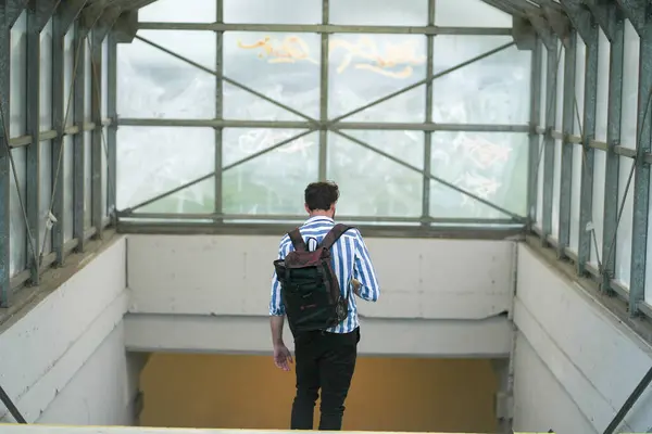 Man with a backpack going downstairs to an underpass