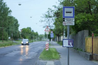 Bus stop and a car passing on a wet looking but dry road