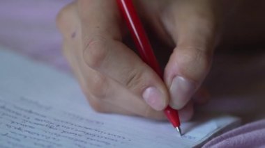 Öğrenci defterine kalemle yazı yazıyor.
