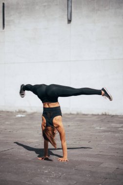 Güçlü kız şehirde denge becerileri geliştiriyor. Şehir geçmişi. Dikey fotoğraf. 