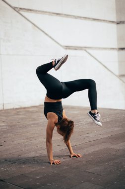 Parkour 'lu kadın şehirde amuda kalkma becerileri sergiliyor. Şehir geçmişi. Dikey fotoğraf. 