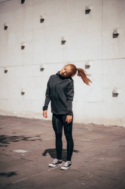 Şehir binasının yakınında ısınıyorum. Siyah gömlekli ve pantolonlu genç bir kız..