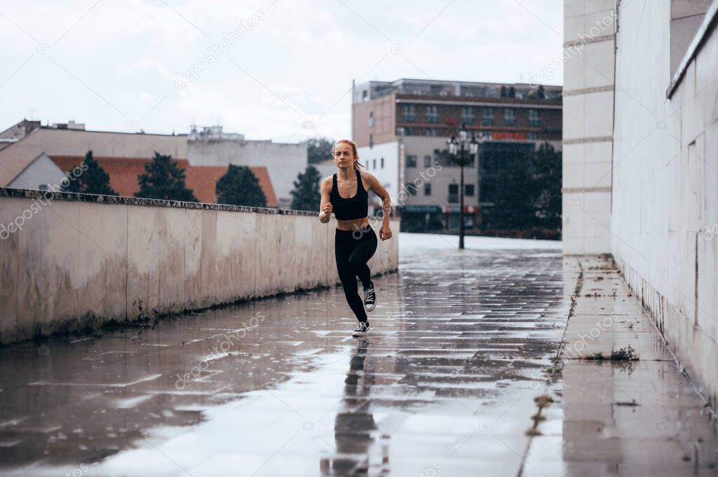 Young sporty woman jogging on the city. Running fitness girl in sportswear outdoor.