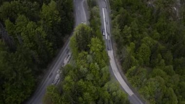 Minibüs gezisi için harika bir manzara. Ağaçların arasındaki sarmal dağ yolunun üstündeki hava aracı görüntüsü.. 