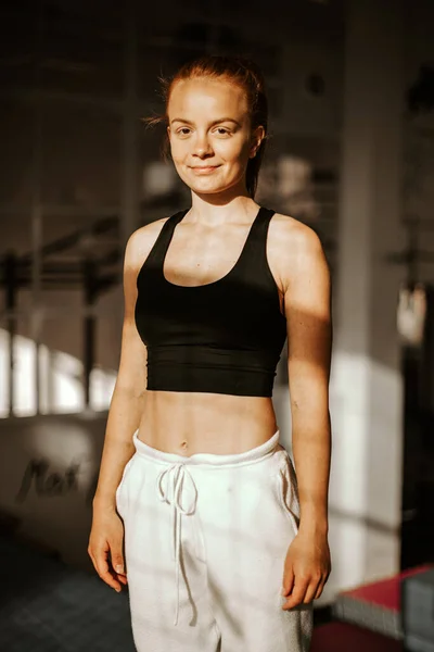 Portre. Spor salonunda spor kıyafetleri içinde gülümseyen genç ve çekici bir bayan atlet. gün batımı