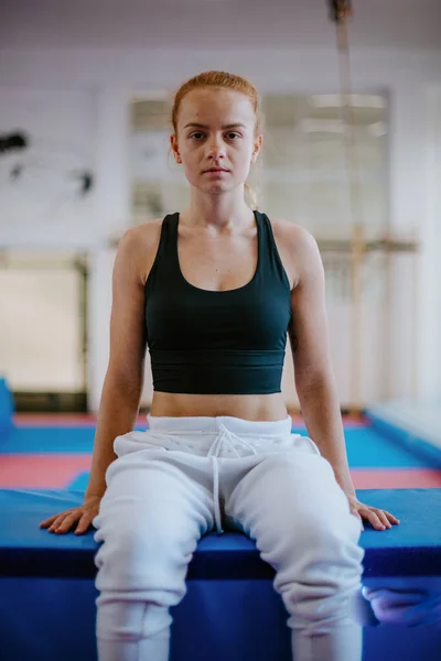 Portrett av en ung, sterk, gymnastisk parkourkvinne som sitter på en hoppende hindring – stockfoto
