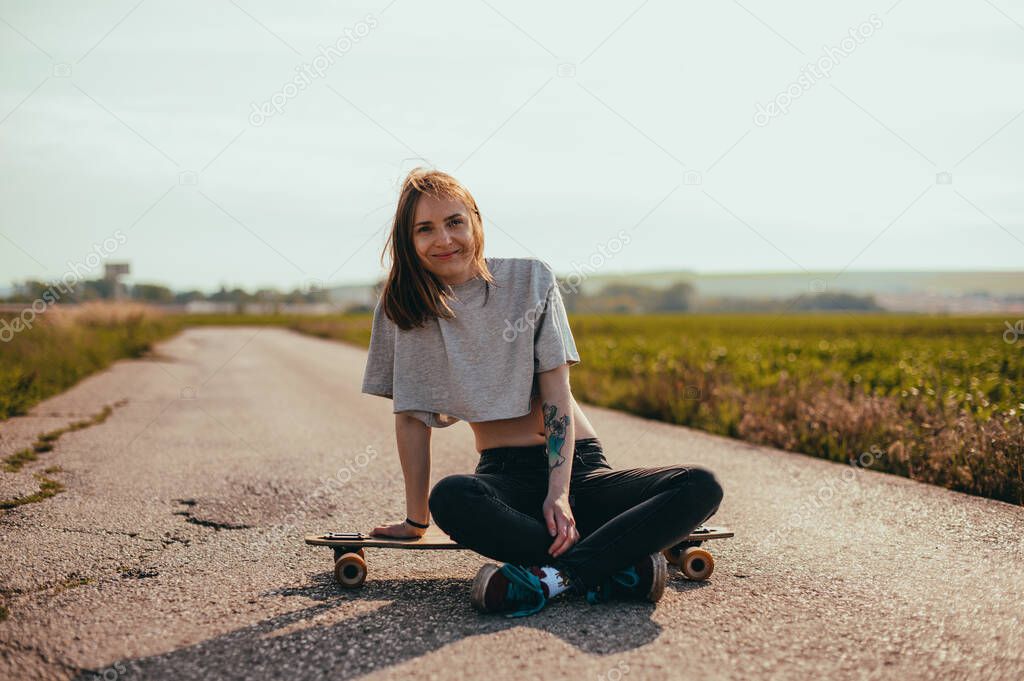 Young cool Woman portrait With Longboard. Girl skater posing on longboard in sunny weather.
