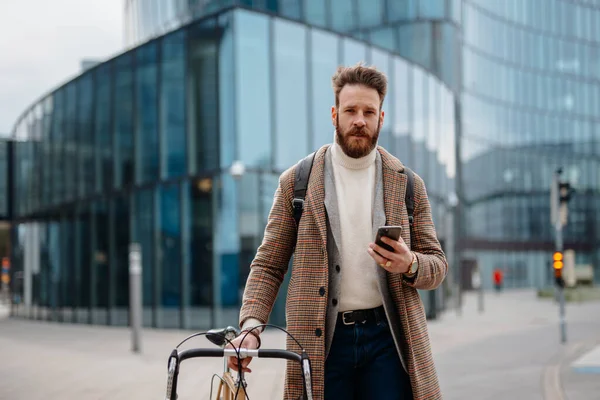 Portrett av hipster forretningsmann med sykkel, med mobil og foran kamera. Forretningssentrum. Komme på jobb – stockfoto