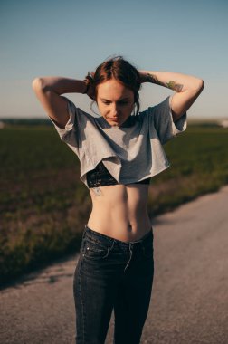 Güzel bir kadın saçlarını didik didik ediyor ve çıplak karnını görüyor. Yaz posteri, güneşli gün