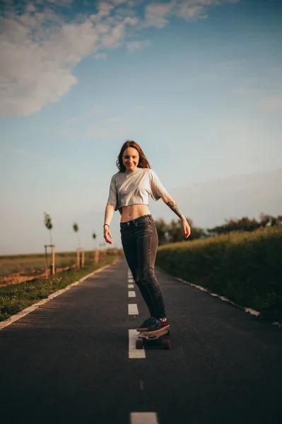 Kobieta jeździ na longboardzie i lubi jeździć za darmo. plakat, baner pionowy, Słoneczny dzień, — Zdjęcie stockowe