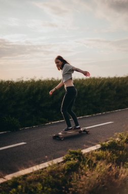 Bir kadın, kollarını açmış, uzun bir tahtaya oyma yapıyor ve bedava gezintiden zevk alıyor. Güneşli gün, poster, uzun tahta günü