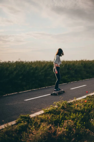 Dziewczyna jeździ na longboardzie i cieszy się darmową przejażdżką. Słoneczny dzień, plakat, baner pionowy longboard day — Zdjęcie stockowe