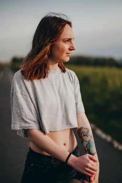 Muotokuva tatuoitu nuori nainen nojaa longboard näyttää ulos ammuttu — kuvapankkivalokuva