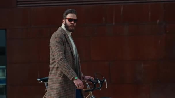 Joven hombre de negocios con bicicleta sobre fondo de pared roja en una ciudad. Fondo de color rojo — Vídeos de Stock